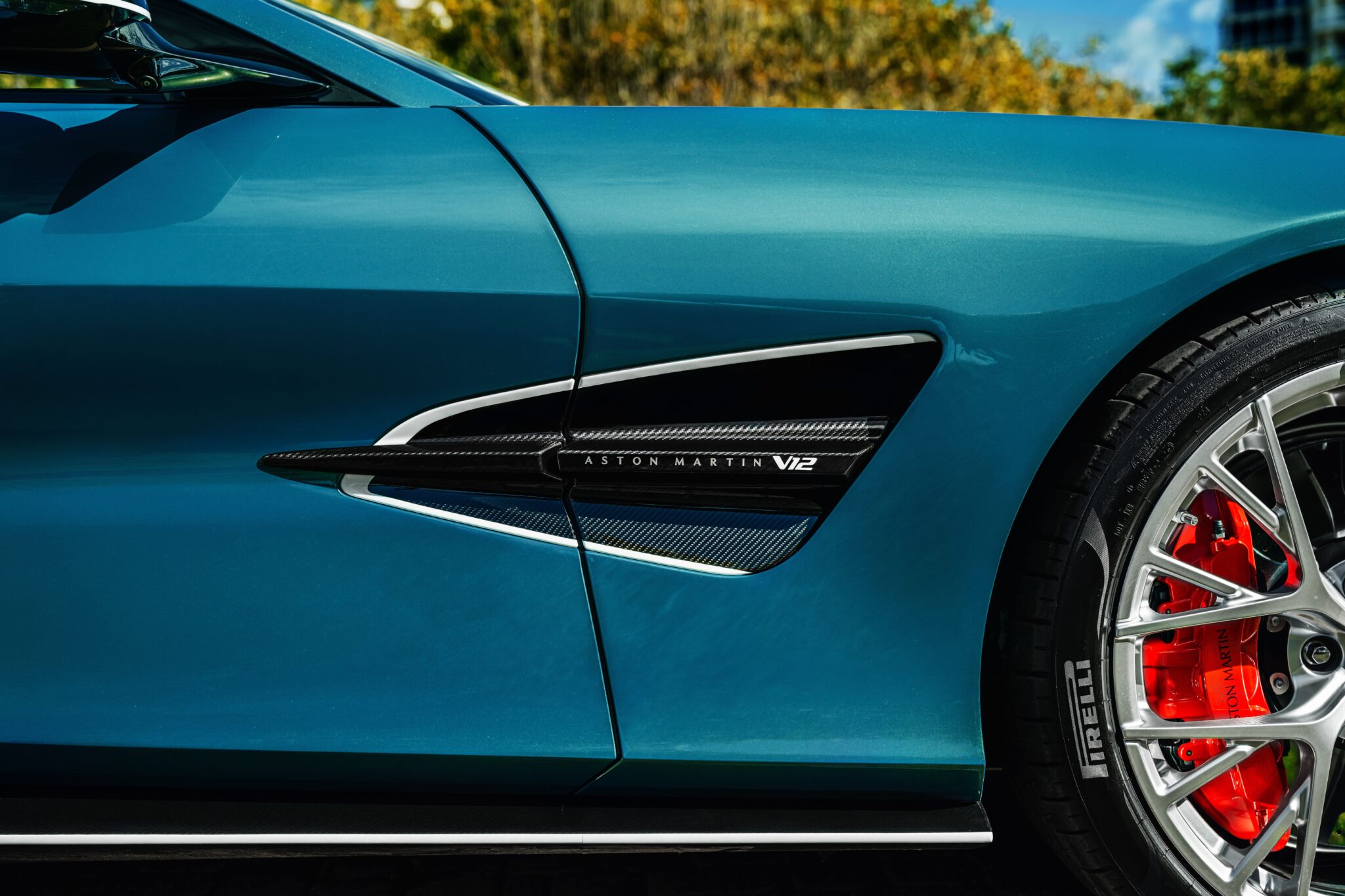 Aston Martin Vanquish Volante cruising along a coastal road at golden hour