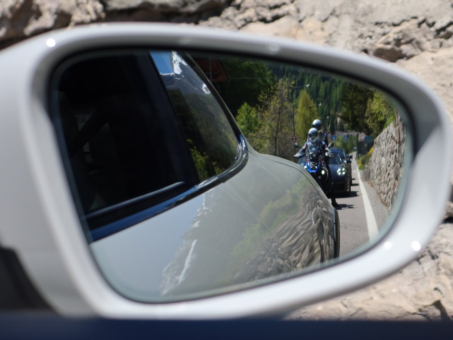 Motorcyclists reflected in a Porsche wing mirror climbing Passo Gardena, Dolomites