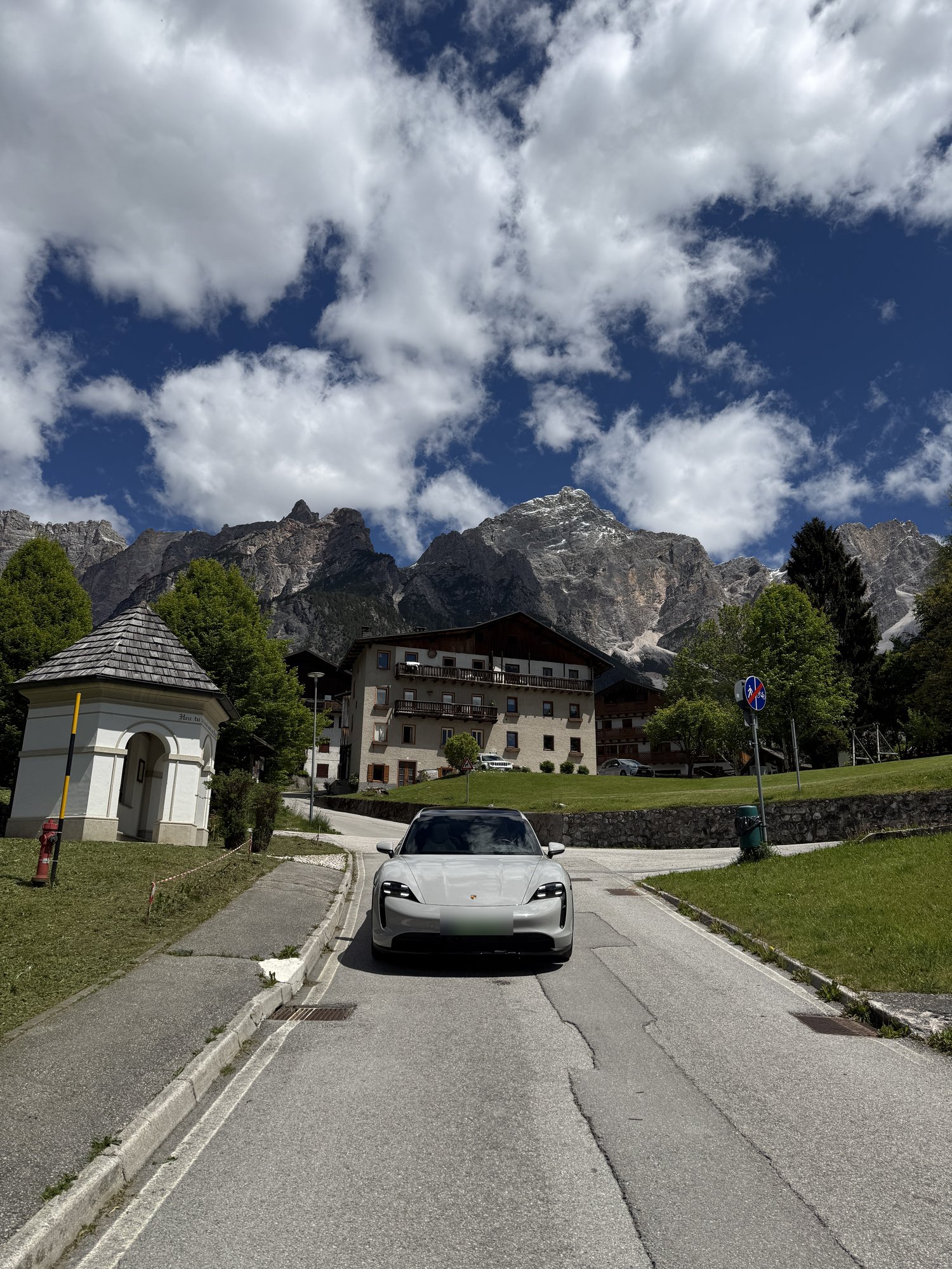 Porsche Taycan Cross Turismo parked on a hairpin below the Sella group, Passo Gardena, Dolomites